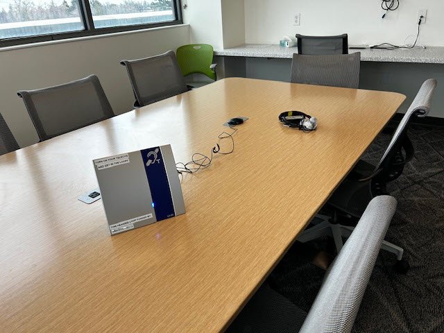 conference room table with portable counter loop, external microphone, and headphones. Approximately 10 people can sit around the table