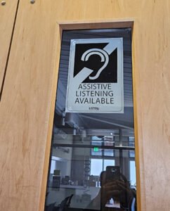 Sign on window "Assistive Listening Available" at city council room