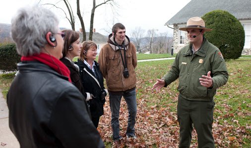 A national Park Service small group tour with a ranger and 4 people circled around him, all wearing a FM receiver and ear loops