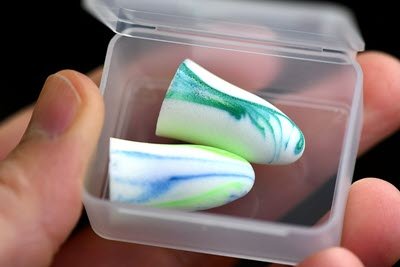 a person holding 2 earplugs in a clear box 